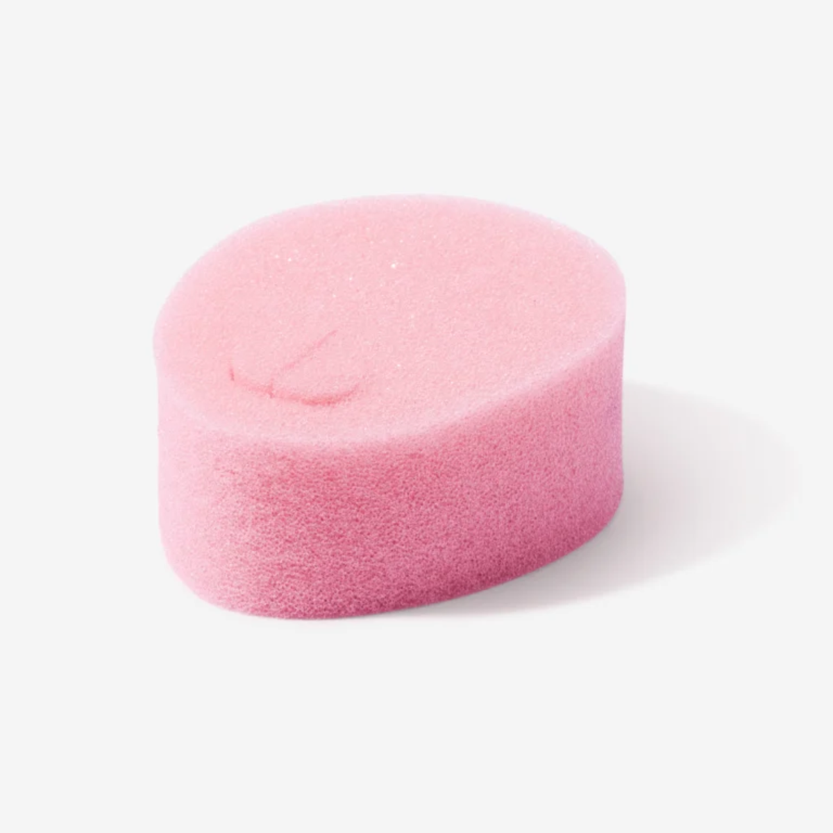 A close-up, studio photograph of a single pink, oval-shaped sponge tampon. It has a soft, porous texture and a small indentation or "removal loop" visible on its top surface. The background is a clean, neutral white.