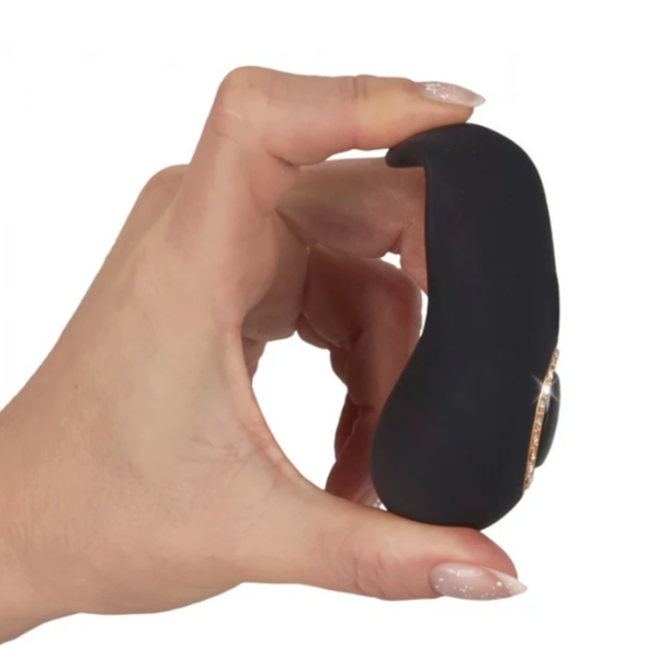 Close-up of a hand demonstrating the flexibility of the matte black clitoral massager by gently bending its curved tip.