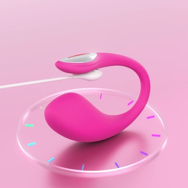 Promotional product shot showing the pink Lovense Lush 4 vibrator connected to its magnetic charging cable on a circular clock-like display base.